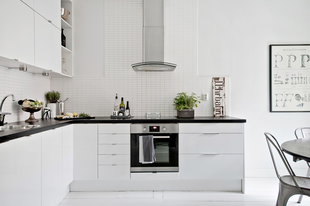 Design ideas for a mid-sized scandinavian l-shaped eat-in kitchen in Gothenburg with flat-panel cabinets, laminate benchtops, white splashback, painted wood floors, no island, white floor, a drop-in sink and stainless steel appliances.