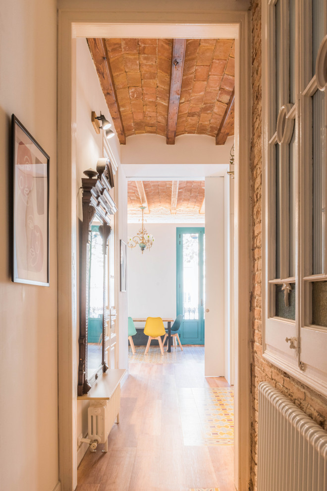 Mid-sized transitional hallway in Barcelona with white walls, vinyl floors, multi-coloured floor, exposed beam and brick walls.