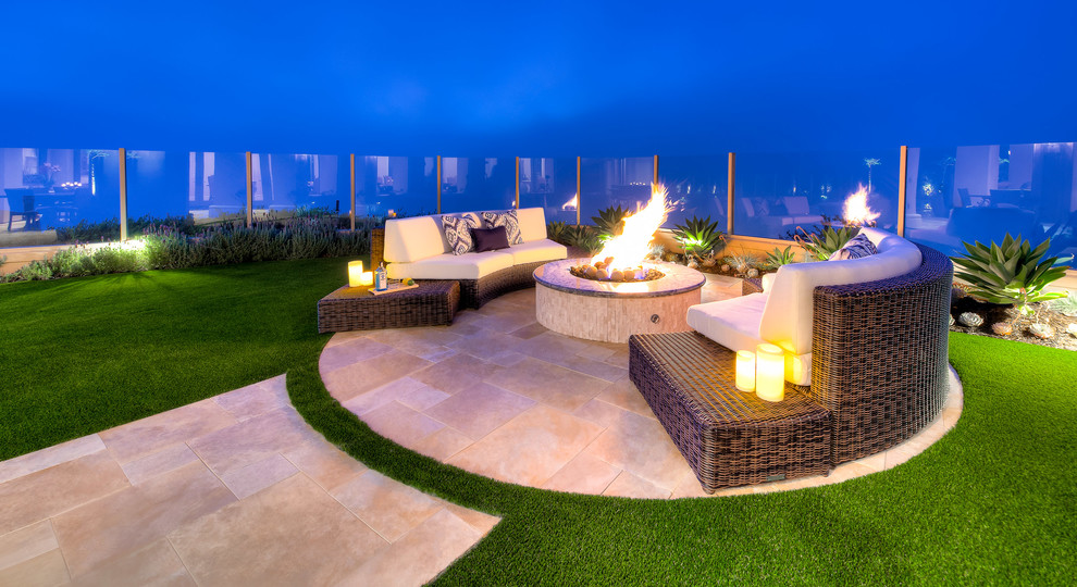 This is an example of a mid-sized contemporary backyard patio in Orange County with a fire feature and natural stone pavers.
