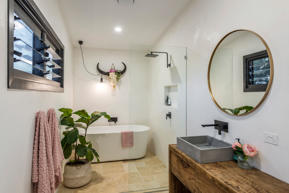 Inspiration for a beach style master wet room bathroom in Gold Coast - Tweed with flat-panel cabinets, medium wood cabinets, a freestanding tub, white walls, a vessel sink, wood benchtops, beige floor, an open shower and brown benchtops.