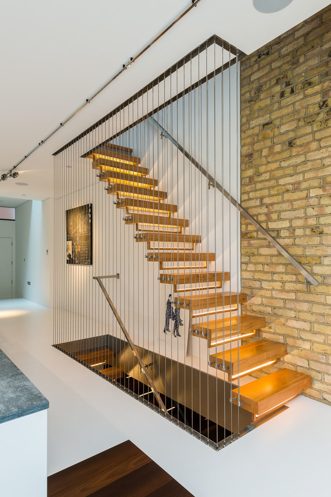 Design ideas for a mid-sized contemporary wood staircase in London with open risers and cable railing.