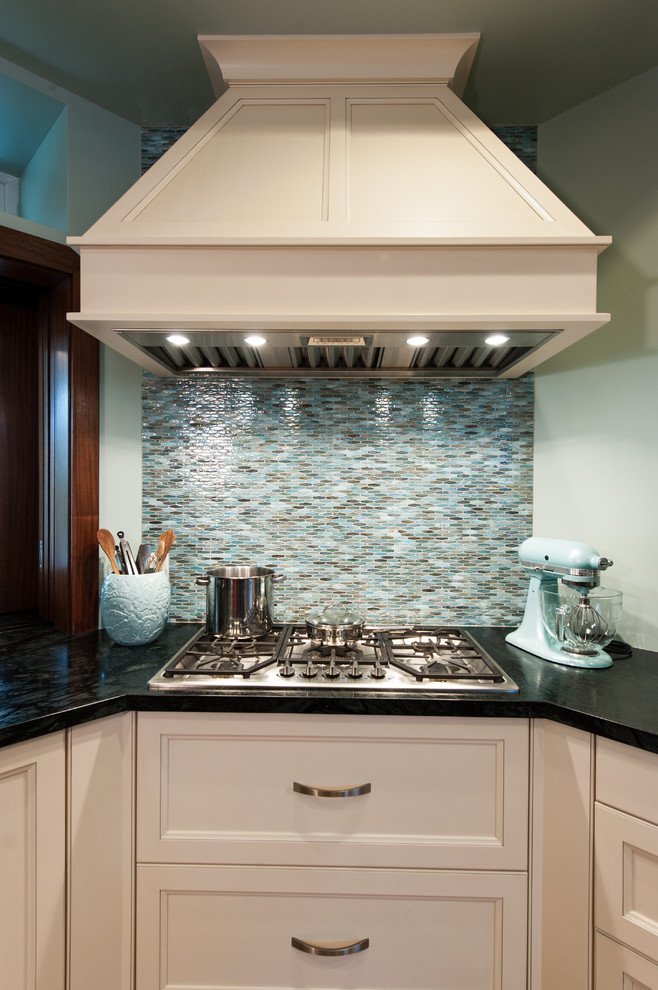 Mid-sized transitional l-shaped open plan kitchen in Hawaii with shaker cabinets, white cabinets, soapstone benchtops, blue splashback, glass sheet splashback, panelled appliances and with island.
