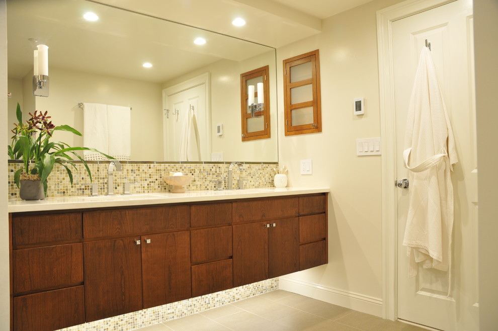 Inspiration for a mid-sized contemporary master bathroom in Boston with an undermount sink, furniture-like cabinets, medium wood cabinets, solid surface benchtops, a corner shower, a one-piece toilet, beige tile, glass tile, beige walls, ceramic floors, grey floor, a hinged shower door and white benchtops.