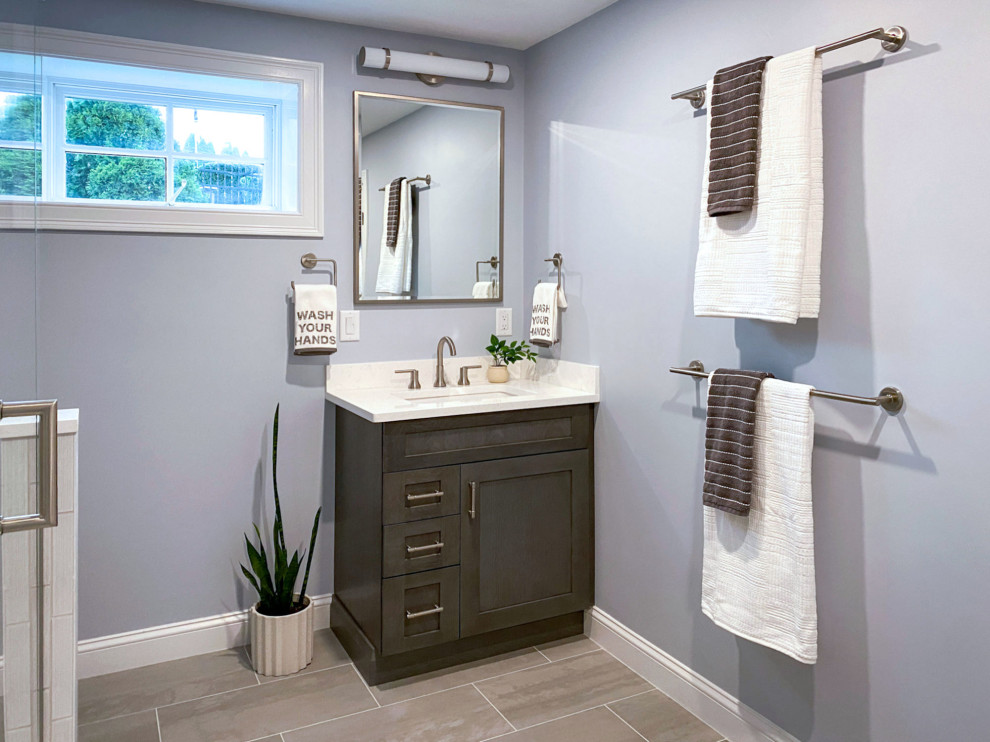 Inspiration for a transitional white tile and ceramic tile porcelain tile, gray floor and single-sink corner shower remodel in Boston with shaker cabinets, gray cabinets, a one-piece toilet, gray walls, an undermount sink, quartz countertops, a hinged shower door, white countertops and a built-in vanity