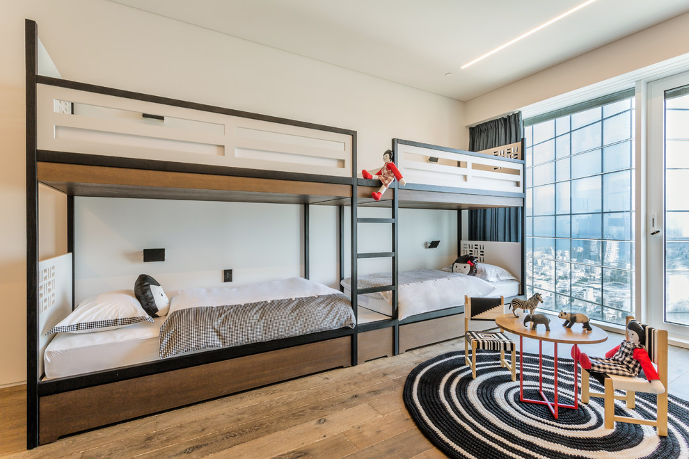 Trendy gender-neutral light wood floor and brown floor kids' bedroom photo in Tel Aviv with white walls