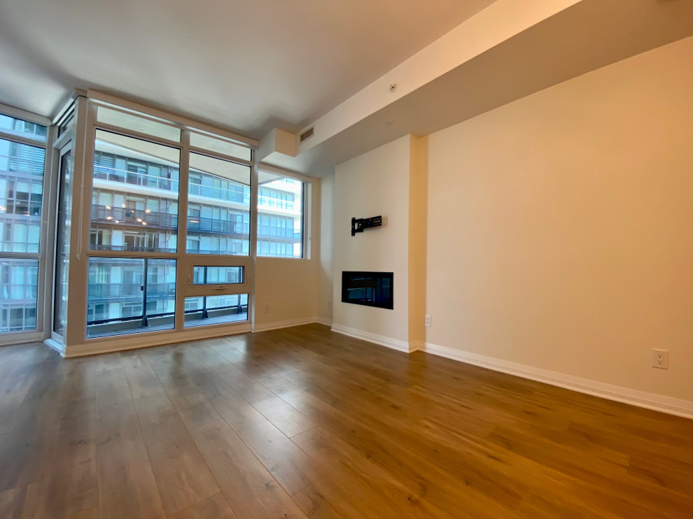 Foto di un piccolo soggiorno contemporaneo aperto con pareti beige, pavimento in laminato, camino sospeso, TV a parete e pavimento marrone