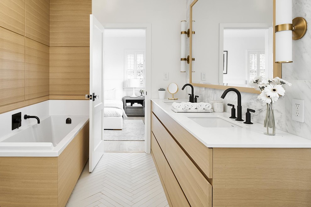 Photo of a mid-sized contemporary master bathroom in Vancouver with flat-panel cabinets, light wood cabinets, a freestanding tub, a corner shower, a one-piece toilet, beige tile, marble, white walls, porcelain floors, an undermount sink, engineered quartz benchtops, beige floor, a hinged shower door and white benchtops.