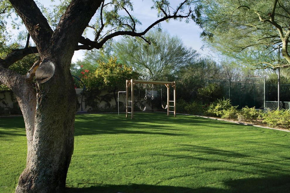 This is an example of a large mediterranean backyard driveway in Phoenix with with outdoor playset.
