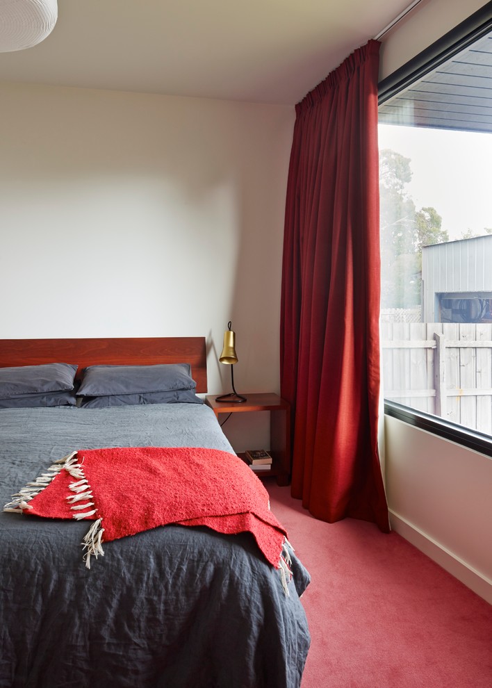 Contemporary bedroom in Melbourne with white walls, carpet and red floor.