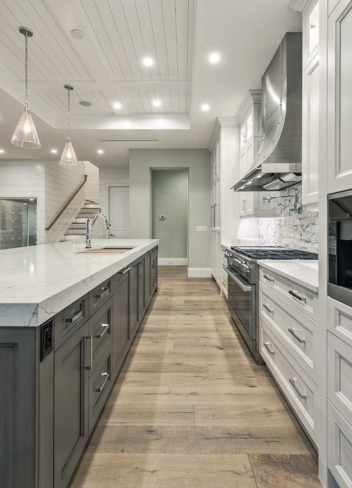 This is an example of a large modern l-shaped open plan kitchen in Miami with an undermount sink, recessed-panel cabinets, grey cabinets, granite benchtops, beige splashback, ceramic splashback, stainless steel appliances, light hardwood floors, with island and brown floor.