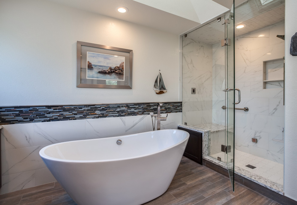 Large contemporary master bathroom in Denver with shaker cabinets, brown cabinets, a japanese tub, a curbless shower, gray tile, white walls, medium hardwood floors, an integrated sink, granite benchtops, brown floor, a hinged shower door, white benchtops, a shower seat, a double vanity and a built-in vanity.