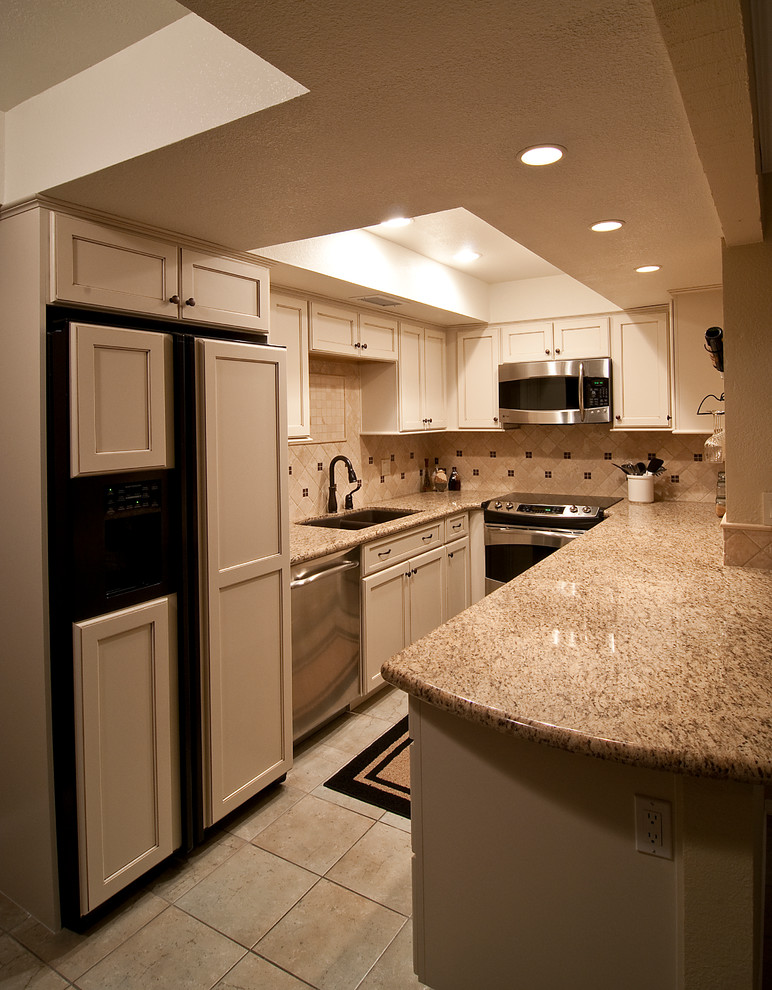 Design ideas for a small transitional u-shaped kitchen in Phoenix with shaker cabinets, white cabinets, granite benchtops, beige splashback, a double-bowl sink, travertine splashback, stainless steel appliances, travertine floors, no island and beige floor.