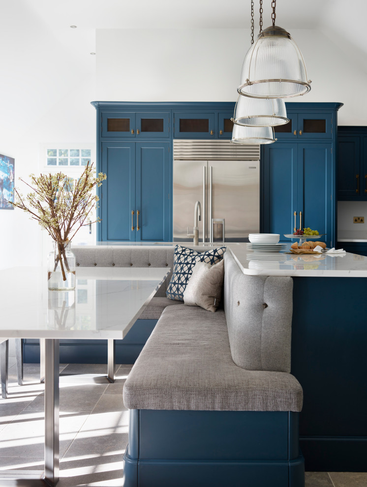 Klassische Wohnküche in L-Form mit Schrankfronten im Shaker-Stil, blauen Schränken, Quarzit-Arbeitsplatte, Küchenrückwand in Weiß, Küchengeräten aus Edelstahl, Kücheninsel und weißer Arbeitsplatte in Essex