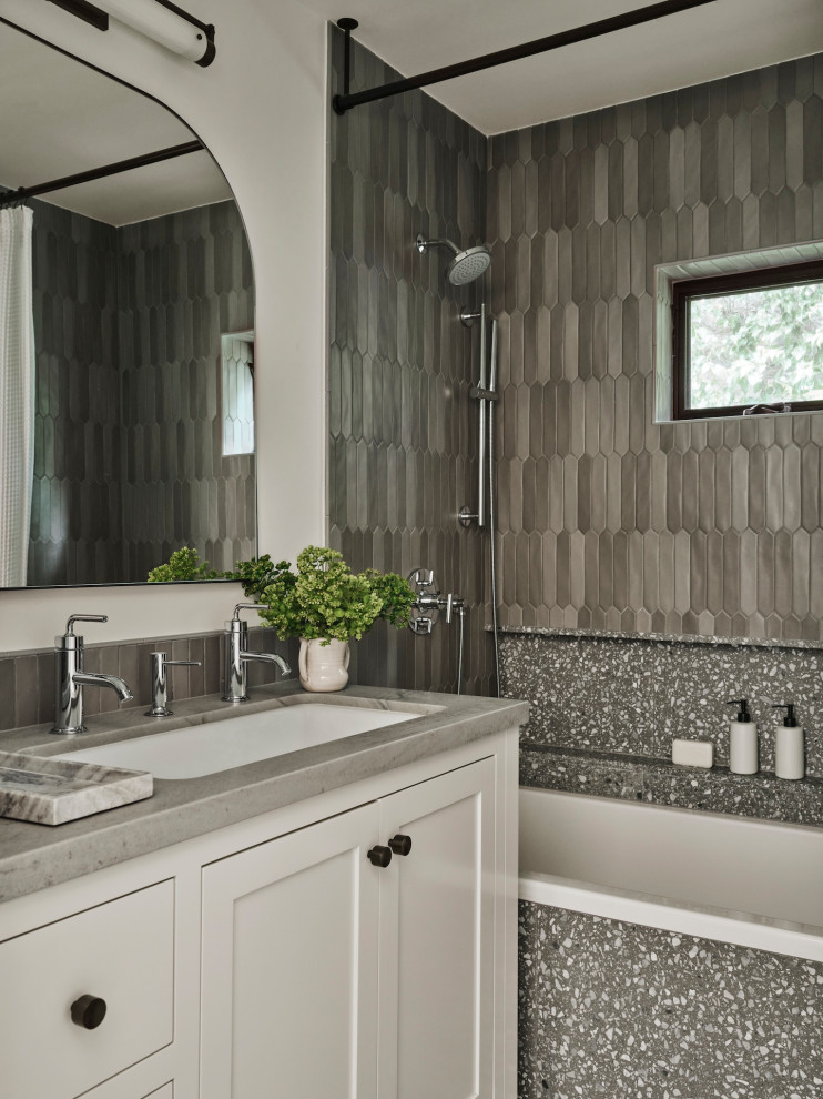 Klassisk inredning av ett grå grått badrum, med skåp i shakerstil, vita skåp, ett badkar i en alkov, en dusch/badkar-kombination, grå kakel, vita väggar, ett undermonterad handfat och dusch med duschdraperi