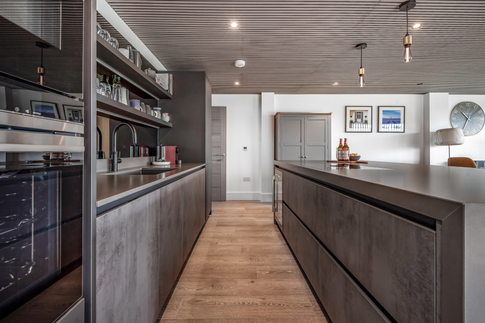 Idéer för ett stort modernt grå linjärt kök med öppen planlösning, med en undermonterad diskho, släta luckor, grå skåp, bänkskiva i koppar, grått stänkskydd, glaspanel som stänkskydd, integrerade vitvaror, en köksö och brunt golv