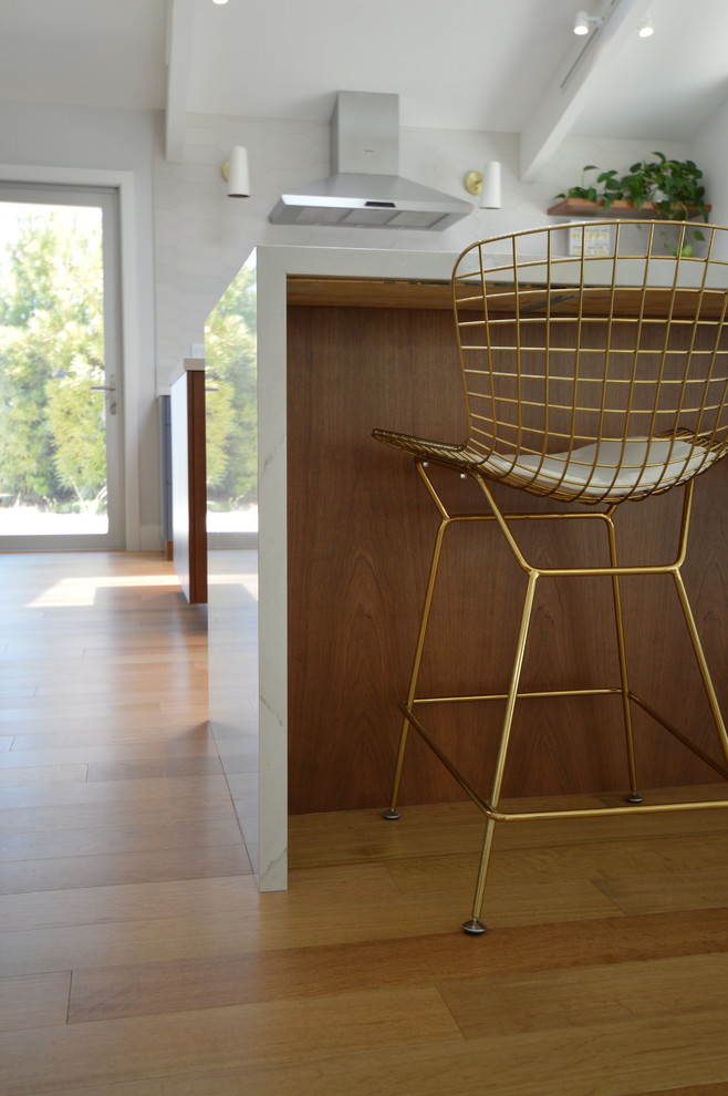 Photo of a large midcentury u-shaped kitchen in Los Angeles with an undermount sink, flat-panel cabinets, blue cabinets, quartzite benchtops, stainless steel appliances, medium hardwood floors, with island, brown floor and white benchtop.