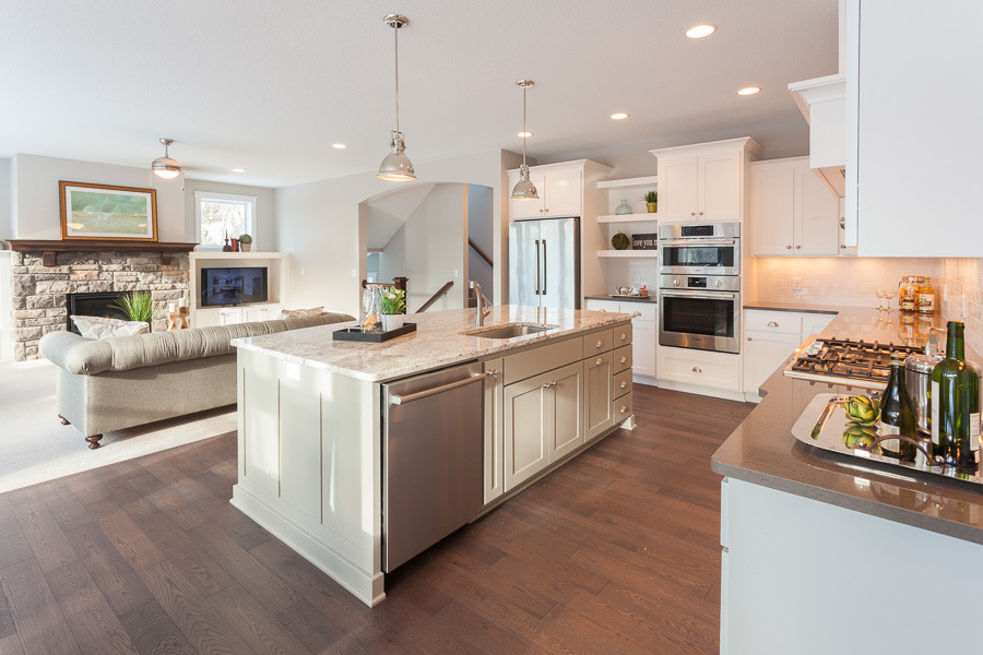 Photo of a large traditional l-shaped eat-in kitchen in Minneapolis with an undermount sink, shaker cabinets, white cabinets, granite benchtops, white splashback, subway tile splashback, stainless steel appliances, medium hardwood floors and with island.
