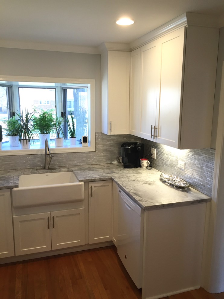 This is an example of a small transitional u-shaped separate kitchen in Chicago with a farmhouse sink, shaker cabinets, white cabinets, granite benchtops, metallic splashback, mosaic tile splashback, white appliances, light hardwood floors and no island.