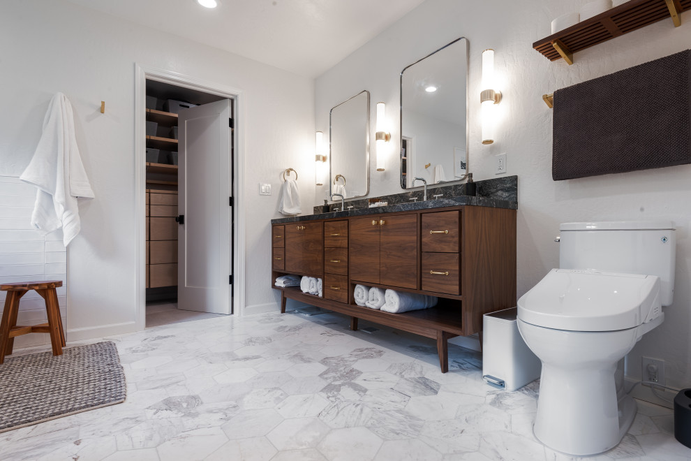 Large contemporary master wet room bathroom in San Francisco with recessed-panel cabinets, brown cabinets, a freestanding tub, white tile, granite benchtops, black benchtops, a double vanity, a freestanding vanity, a two-piece toilet, white walls, porcelain floors, a drop-in sink, white floor and a hinged shower door.