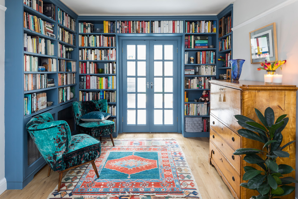 Photo of a mid-sized traditional living room in London with a library, light hardwood floors and no fireplace.