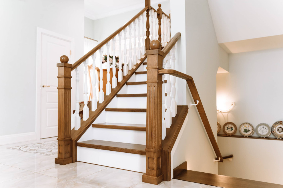 Modelo de escalera en U clásica grande con escalones de madera, contrahuellas de madera, barandilla de madera y panelado