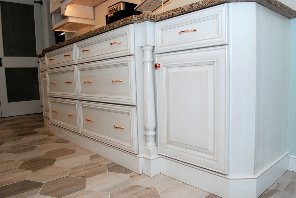 Inspiration for a mid-sized transitional l-shaped porcelain tile and beige floor enclosed kitchen remodel in New York with an undermount sink, raised-panel cabinets, white cabinets, solid surface countertops, white backsplash, porcelain backsplash, stainless steel appliances and an island