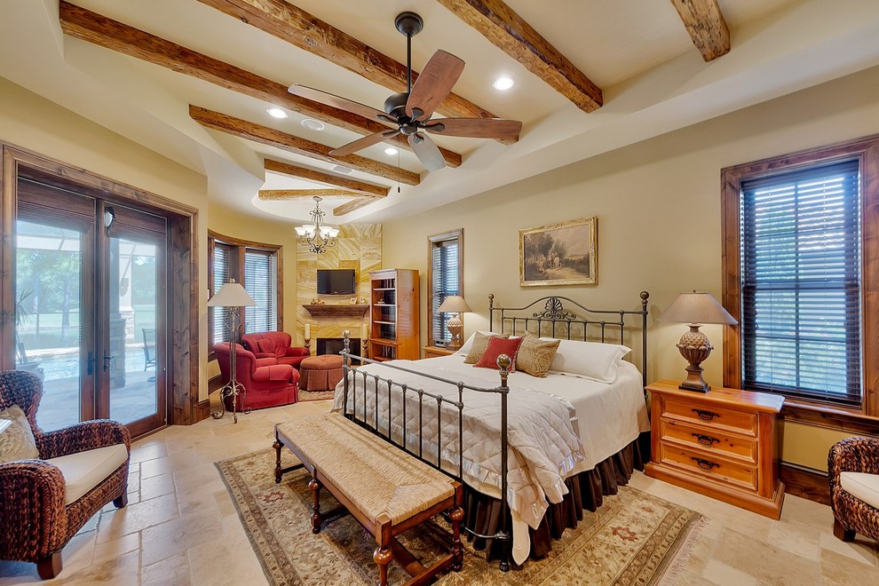 Inspiration for a large traditional master bedroom in Miami with beige walls, travertine floors, a standard fireplace, a tile fireplace surround and brown floor.