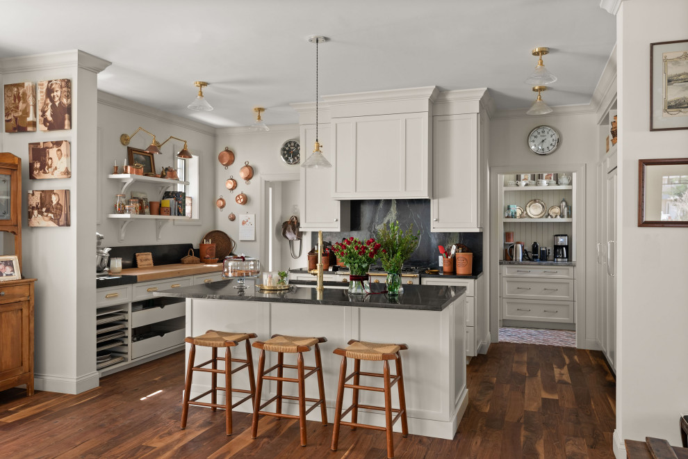 Kitchen - traditional u-shaped dark wood floor and brown floor kitchen idea in Orlando with an undermount sink, shaker cabinets, gray cabinets, black backsplash, stone slab backsplash, an island and black countertops