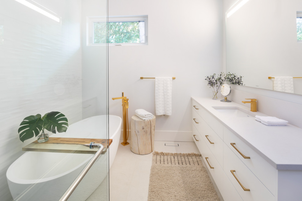 Design ideas for a mid-sized midcentury master bathroom in Vancouver with flat-panel cabinets, white cabinets, a freestanding tub, a curbless shower, a one-piece toilet, white tile, ceramic tile, white walls, porcelain floors, an undermount sink, engineered quartz benchtops, grey floor, a hinged shower door and grey benchtops.