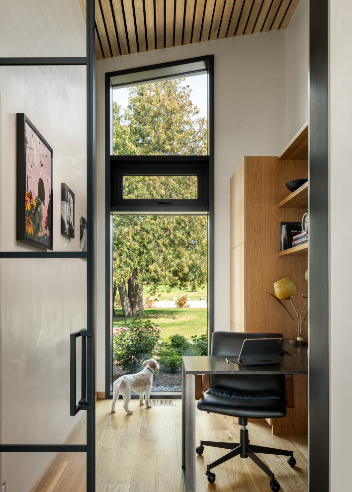 Diseño de despacho contemporáneo pequeño con paredes beige, suelo de madera clara, escritorio empotrado y madera