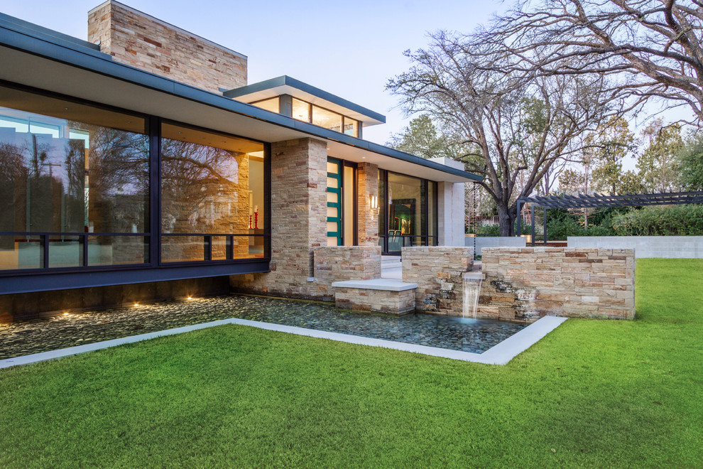 Design ideas for a mid-sized modern full sun backyard stone landscaping in Austin for fall.