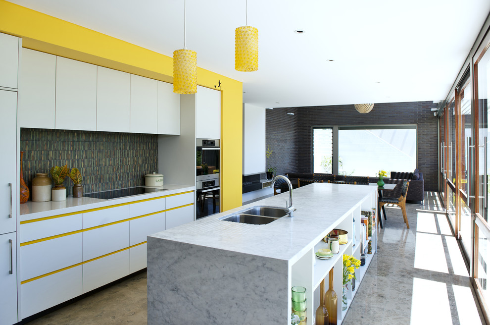 Photo of a midcentury single-wall open plan kitchen in Perth with a double-bowl sink, flat-panel cabinets, white cabinets, stainless steel appliances and with island.
