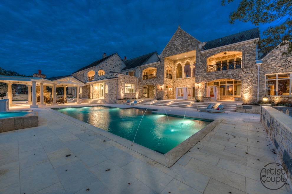 Expansive traditional backyard rectangular pool in Austin with a water feature and natural stone pavers.