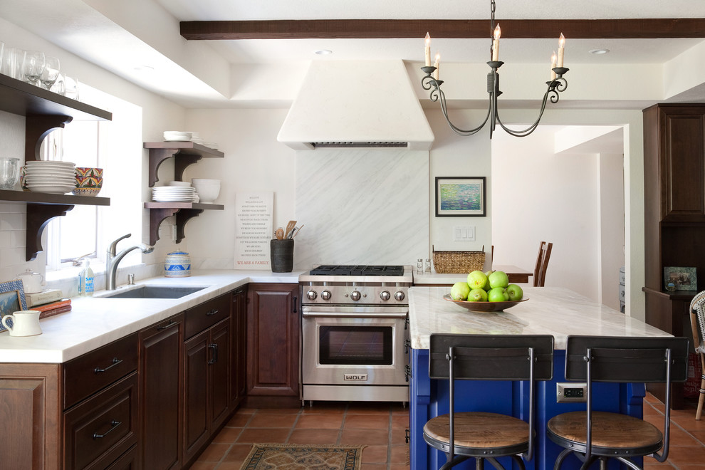 Inspiration for a large mediterranean l-shaped eat-in kitchen in Santa Barbara with dark wood cabinets, marble benchtops, white splashback, stone slab splashback, stainless steel appliances, terra-cotta floors and with island.