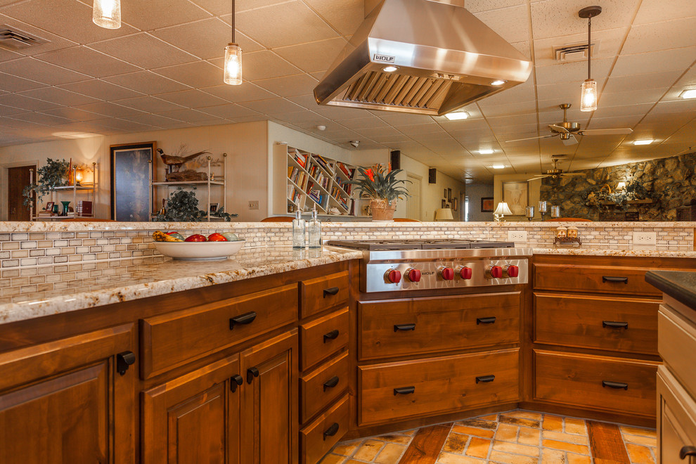 Inspiration for a large country l-shaped eat-in kitchen in Dallas with a double-bowl sink, raised-panel cabinets, medium wood cabinets, granite benchtops, beige splashback, ceramic splashback, stainless steel appliances, brick floors and multiple islands.