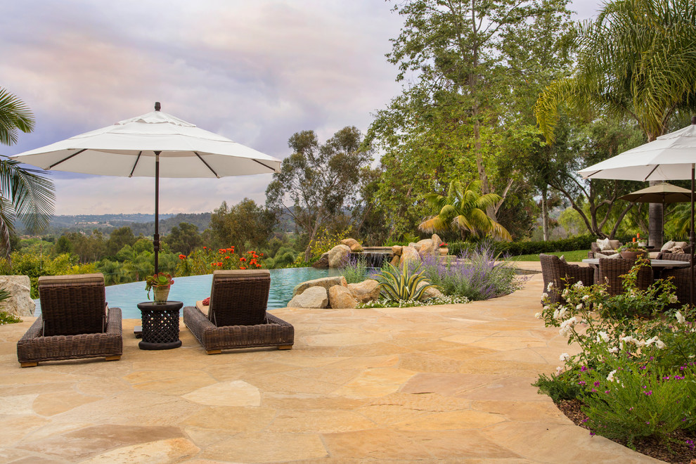 Inspiration for a large country backyard full sun formal garden in San Diego with natural stone pavers.