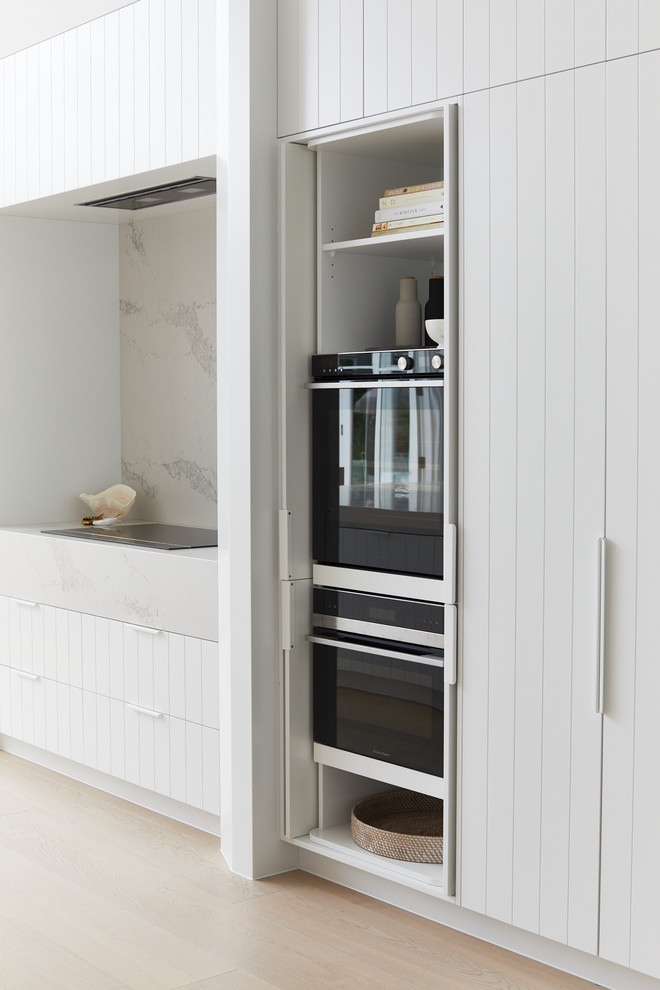 Large beach style galley eat-in kitchen in Sydney with an undermount sink, white cabinets, white splashback, panelled appliances, with island and white benchtop.