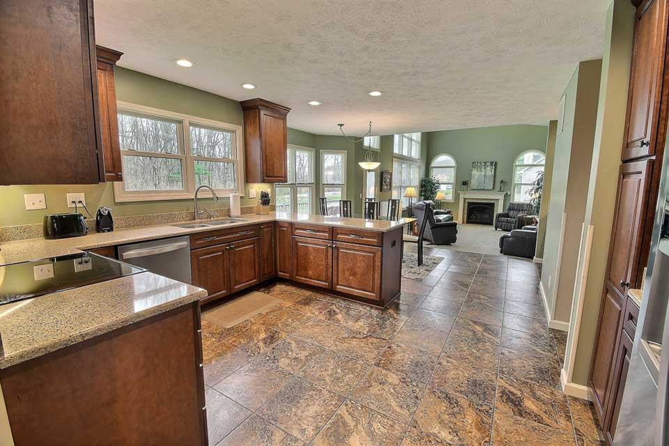 Large transitional u-shaped open plan kitchen in Other with an undermount sink, raised-panel cabinets, medium wood cabinets, quartz benchtops, stainless steel appliances, vinyl floors, no island, beige floor and beige benchtop.