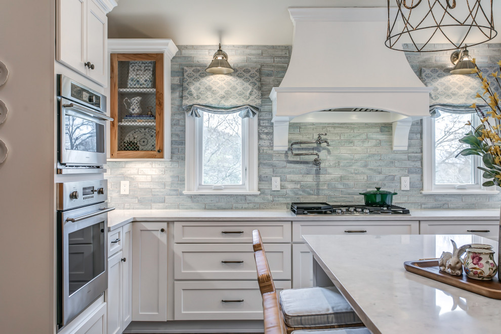 Immagine di una grande cucina con ante in stile shaker, ante bianche, paraspruzzi blu, pavimento in legno massello medio, pavimento marrone e top bianco