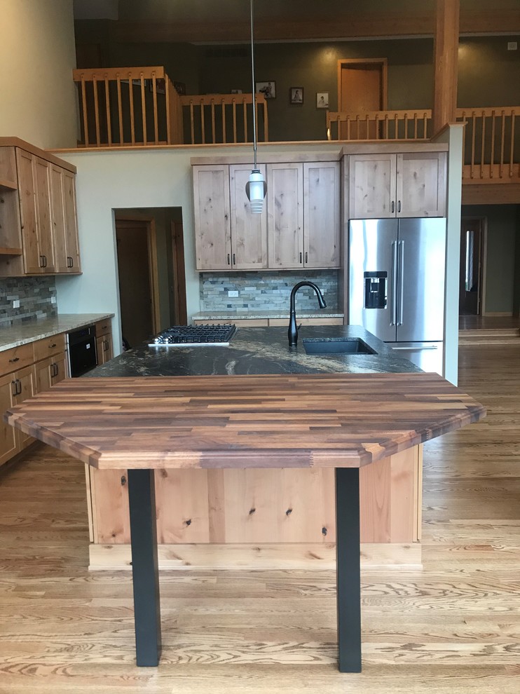 Open concept kitchen - large rustic l-shaped medium tone wood floor and brown floor open concept kitchen idea in Chicago with an undermount sink, shaker cabinets, medium tone wood cabinets, granite countertops, green backsplash, slate backsplash, stainless steel appliances, an island and black countertops