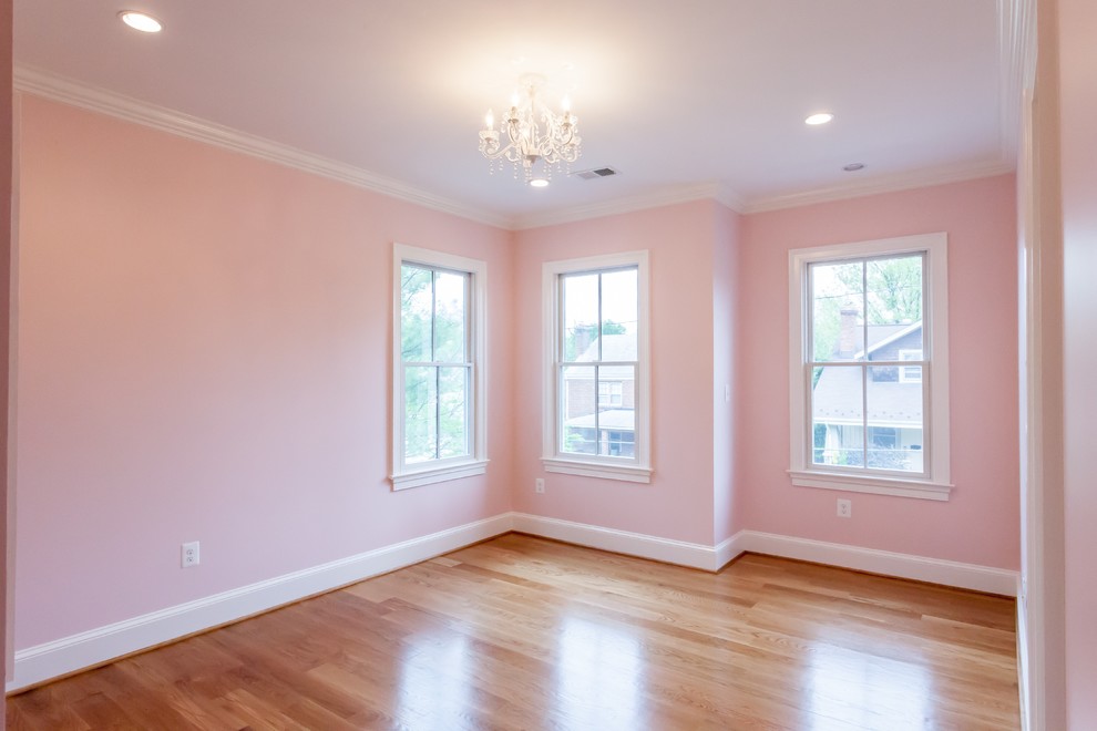 Photo of a country guest bedroom in DC Metro with pink walls, light hardwood floors, no fireplace and brown floor.