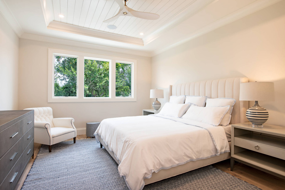 Large beach style guest bedroom in Miami with white walls, light hardwood flooring and a coffered ceiling.