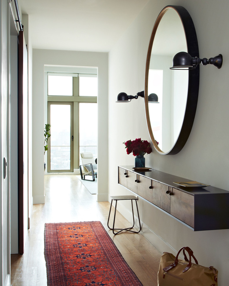 Inspiration for a scandinavian entry hall in New York with white walls and light hardwood floors.