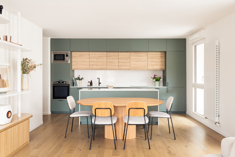 Idéer för mellanstora skandinaviska linjära vitt kök med öppen planlösning, med en integrerad diskho, luckor med profilerade fronter, gröna skåp, bänkskiva i kvartsit, vitt stänkskydd, rostfria vitvaror, ljust trägolv och en köksö