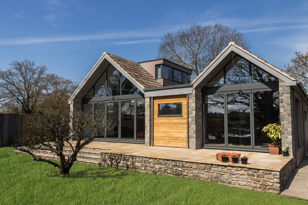 Contemporary one-storey exterior in Other with stone veneer and a gable roof.