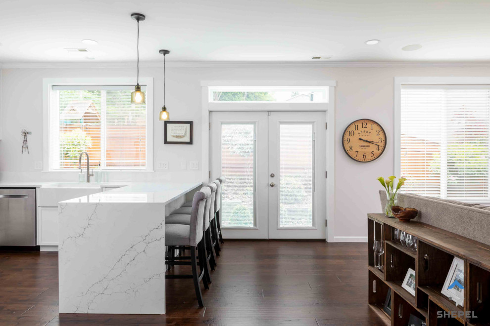 Example of a mid-sized transitional u-shaped dark wood floor and brown floor eat-in kitchen design in Seattle with a farmhouse sink, flat-panel cabinets, white cabinets, quartz countertops, gray backsplash, subway tile backsplash, stainless steel appliances, a peninsula and white countertops