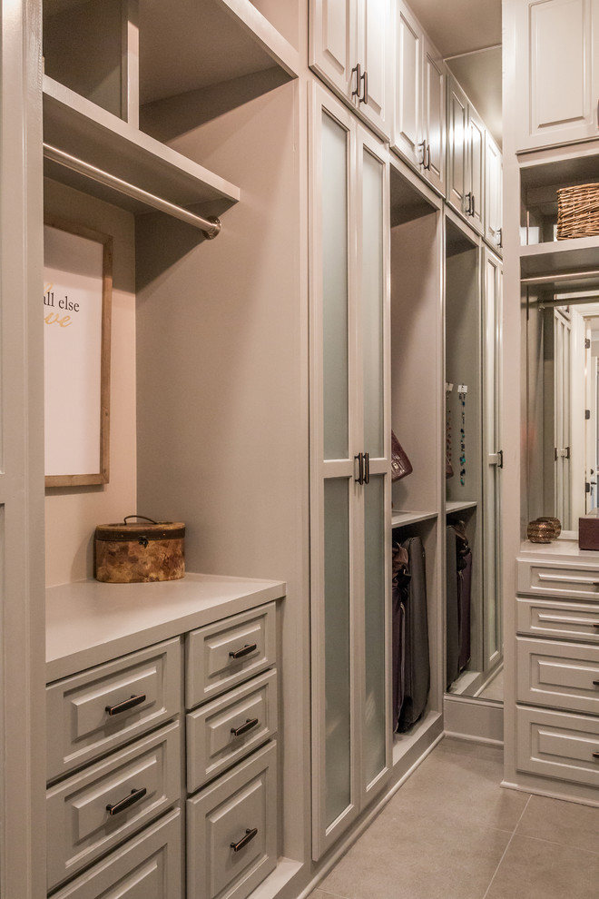 This is an example of an expansive transitional gender-neutral walk-in wardrobe in Other with raised-panel cabinets, brown cabinets, porcelain floors and brown floor.
