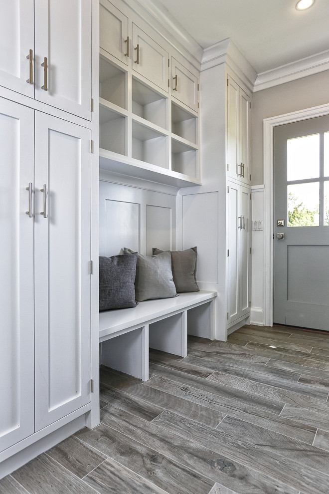 Mid-sized beach style mudroom in New York with white walls, light hardwood floors, a single front door, a gray front door and grey floor.