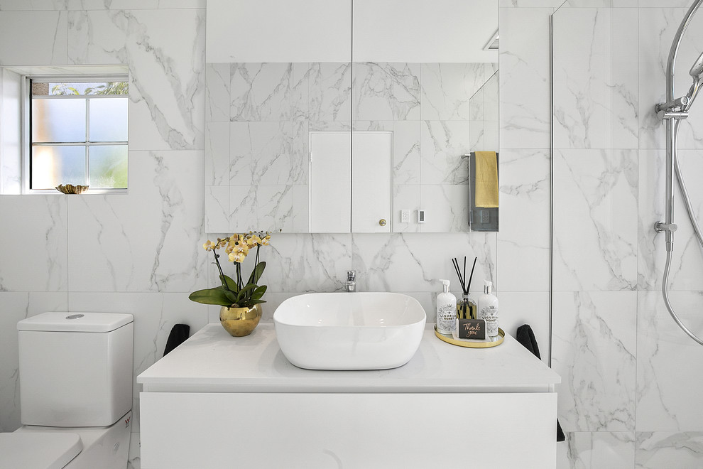 Photo of a large contemporary master wet room bathroom in Sydney with furniture-like cabinets, white cabinets, a freestanding tub, a two-piece toilet, black and white tile, ceramic tile, white walls, ceramic floors, a vessel sink, marble benchtops, white floor, an open shower and white benchtops.