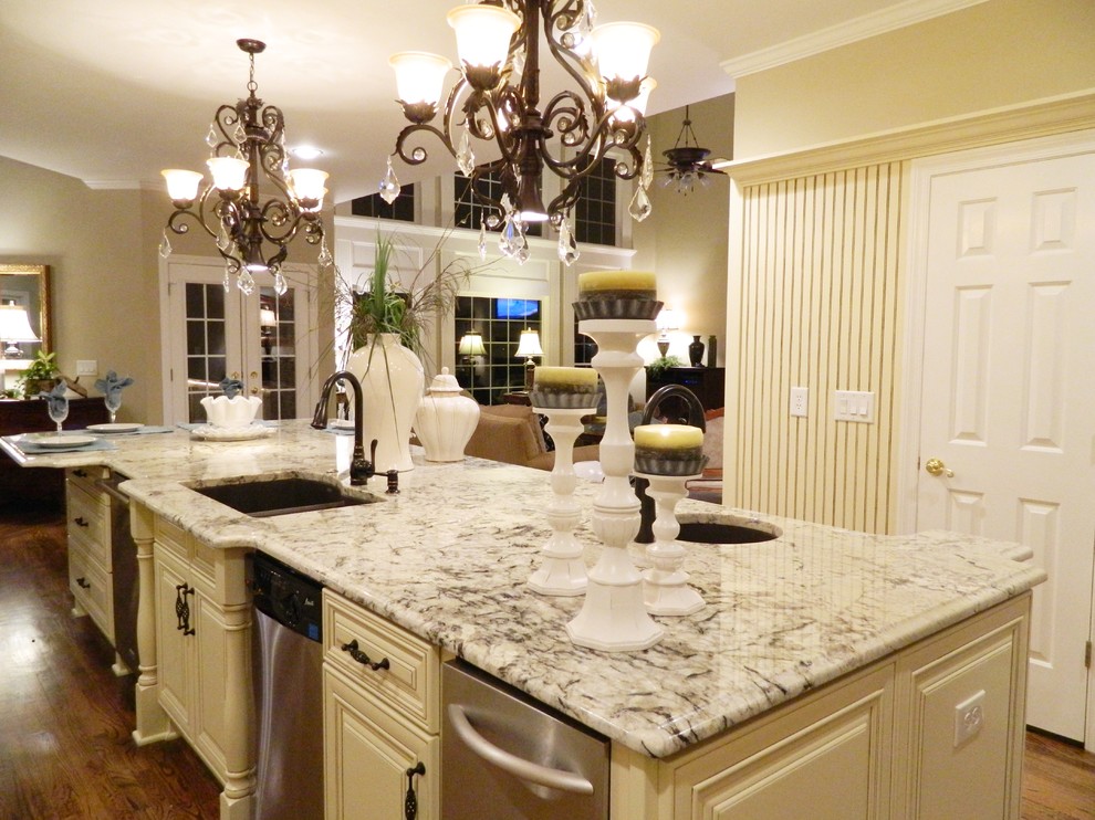 Photo of a mid-sized traditional l-shaped separate kitchen in Atlanta with a double-bowl sink, raised-panel cabinets, white cabinets, granite benchtops, grey splashback, stone slab splashback, stainless steel appliances, dark hardwood floors, with island and brown floor.